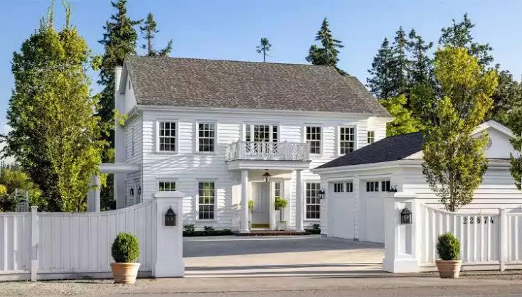 White modern home with dark roof and gated drive